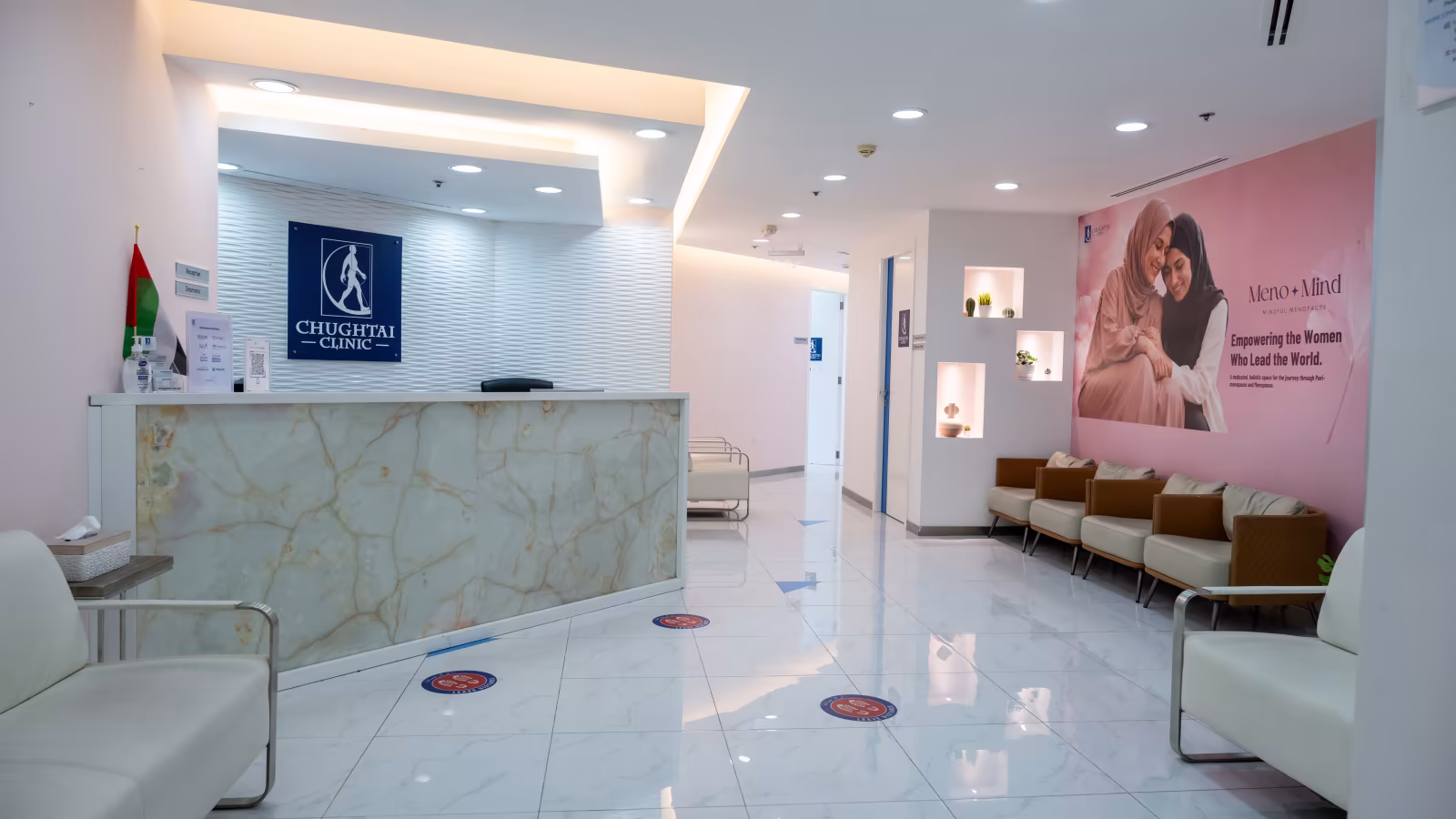Front desk at Chughtai Clinic Dubai with the UAE flag and the Meno Mind women's health wall behind it